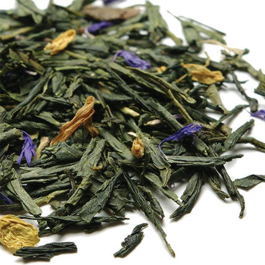 Pile of green tea leaves with some dried flowers on a white background