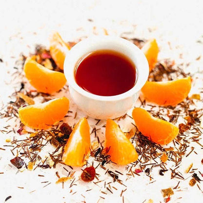 Tea cup with orange slices and dried herbs on a white background