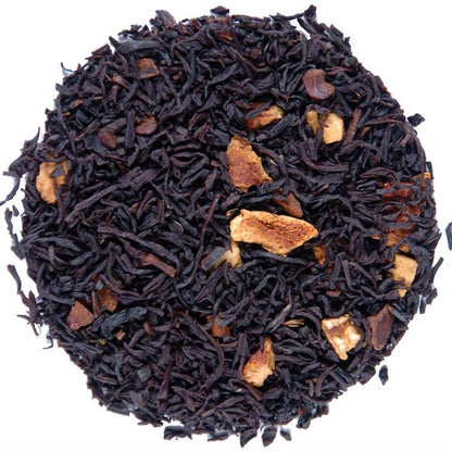 A circular pile of loose-leaf tea blend on a plain white background. The tea consists of very dark brown to near-black dried leaves with scattered light tan dried fruit pieces.