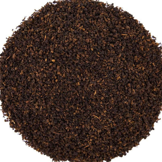 A circular pile of dark brown coffee grounds or tea leaves on a solid white background.